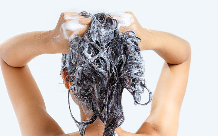 Woman washing hair with shampoo