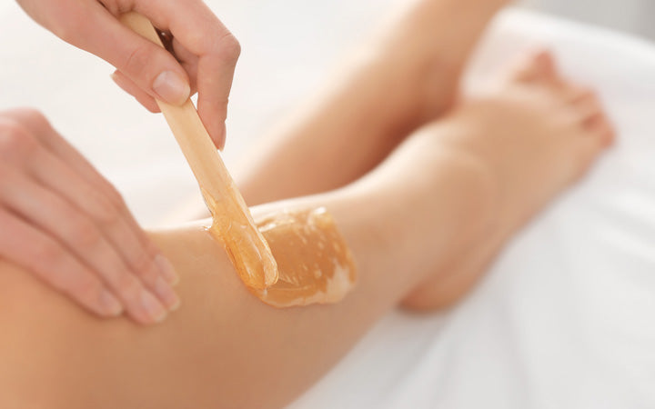 beautician waxing female legs spa