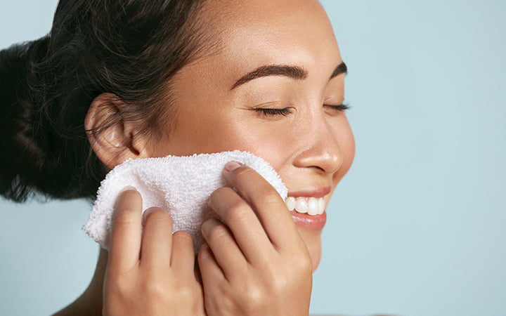 woman cleaning facial skin with towel after washing face