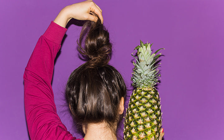 woman with pineapple hairstyle and pineapple in hand