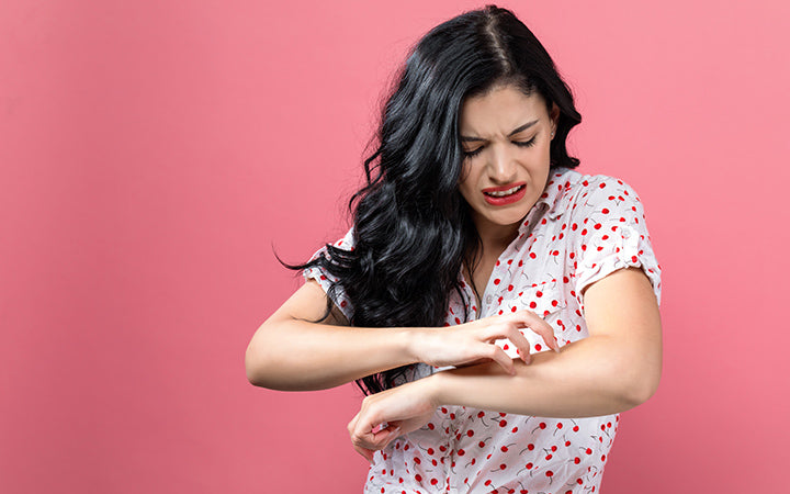 young woman scratching her itchy arm