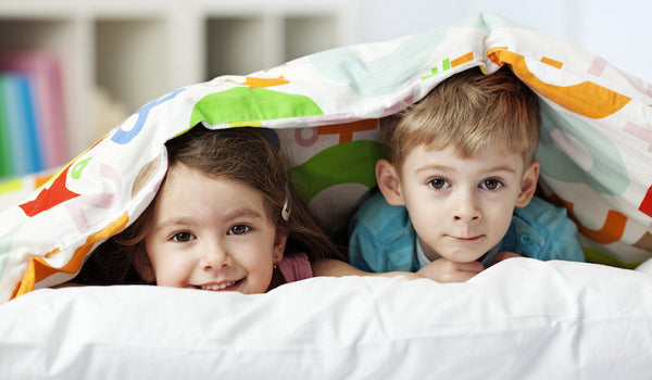 Kids in bed with blanket.