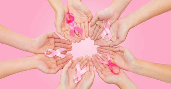 close up of women hands with cancer awareness ribbons over pink background