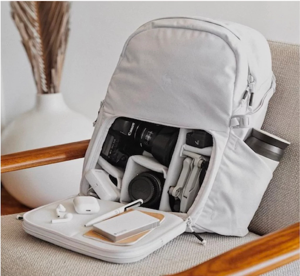 Gray backpack with camera gear and electronics on a chair.
