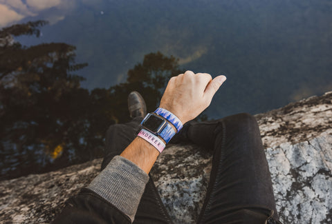 Model wearing a "Wanderer" Apple Watchband and wristband in nature over a small lake or pond.