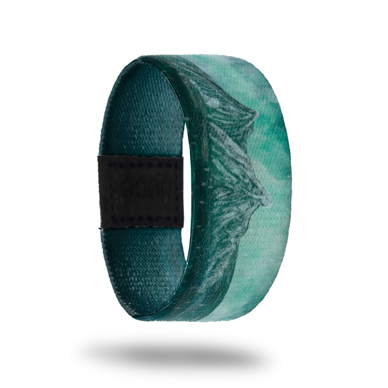 This is a reversible strap. The design is various colors of teal with the scene of mountains in the distance.  The inside is all teal gradient and says Beneath the Surface. It is reversible. 