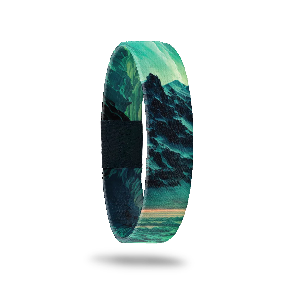 A single wristband with an image of mountains. Colors are teals, blues and greens. Inside reads Dare To Dream. 