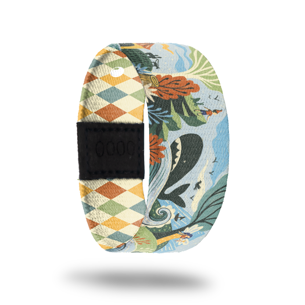 ZOX strap with cartoon design of little boy watching a whale in the ocean on the side of a mountain. Colors are muted orange, beige, blue and green. Comes with a matching pin and collector's box. 