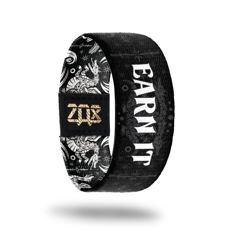 Inside Design of Earn It: black strap with grey design of two headed beast being slayed by knights with white text 'Earn It'