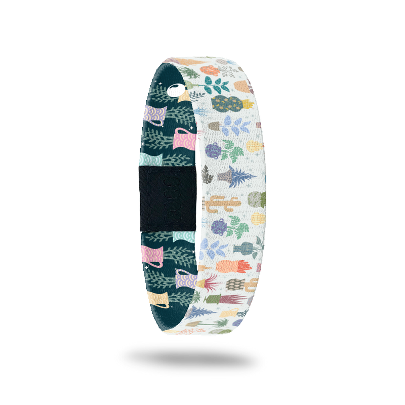 Wristband single with white base and plants/cactus all over in multiple colors. Inside is the same except with a navy blue base and says Grow With It. Comes with a matching pin and collector's box.
