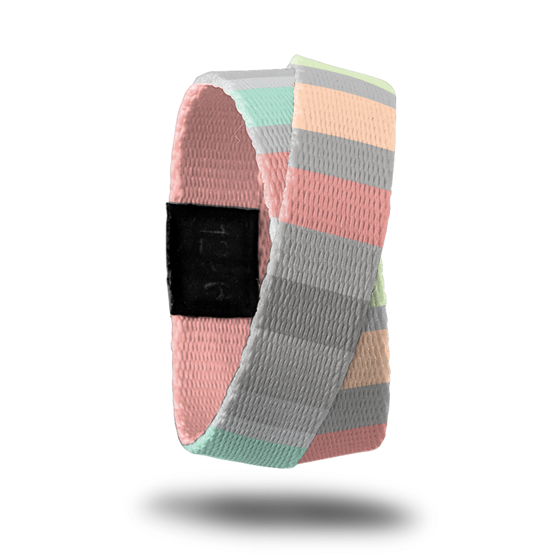 Outside design of How Will You Be Remembered? Subtle knitted look to the design with varying width sizes of rectangles of colors like gray, pink, light orange,and light green. This product, called a double, is thinner and wraps around your wrist twice with the material crossing at one point. 