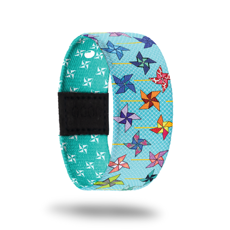 Wristband strap is light blue with pinwheels of diffretn colors all over. The inside is darker teal with white pinwheels and says Its Your Turn. Comes with a matching pin and collector's box. 