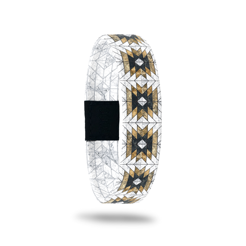 Single wristband with a white base. It has black and gold tribal, geometric designs all over. The inside is the same and says Love Who You Are. 