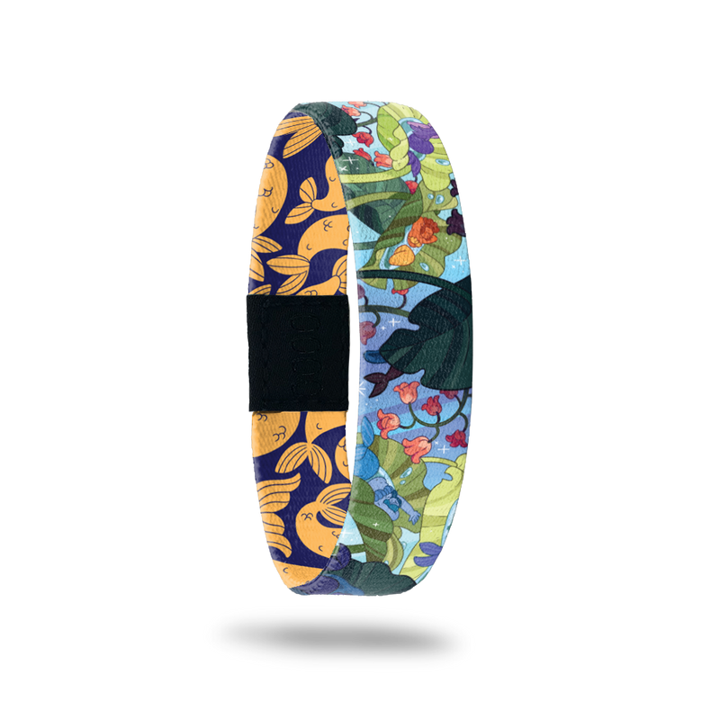 Wristband single is a bluw background with an under the sea image of plant life, fish, etc. The inside is blue and orange mermaid tails and says Make A Splash. This can be purchased with a matching Mermaid charm or separately. 