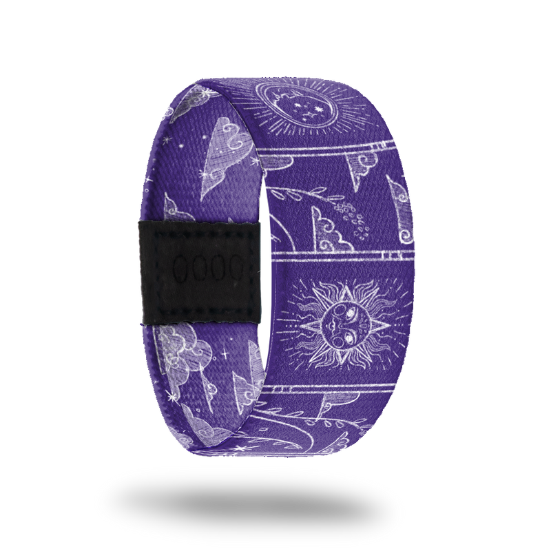 Wristband strap that is purple all over and has white outlines of moons, sodiac images, clouds, vines and suns. The inside is the same and says Make It Count.