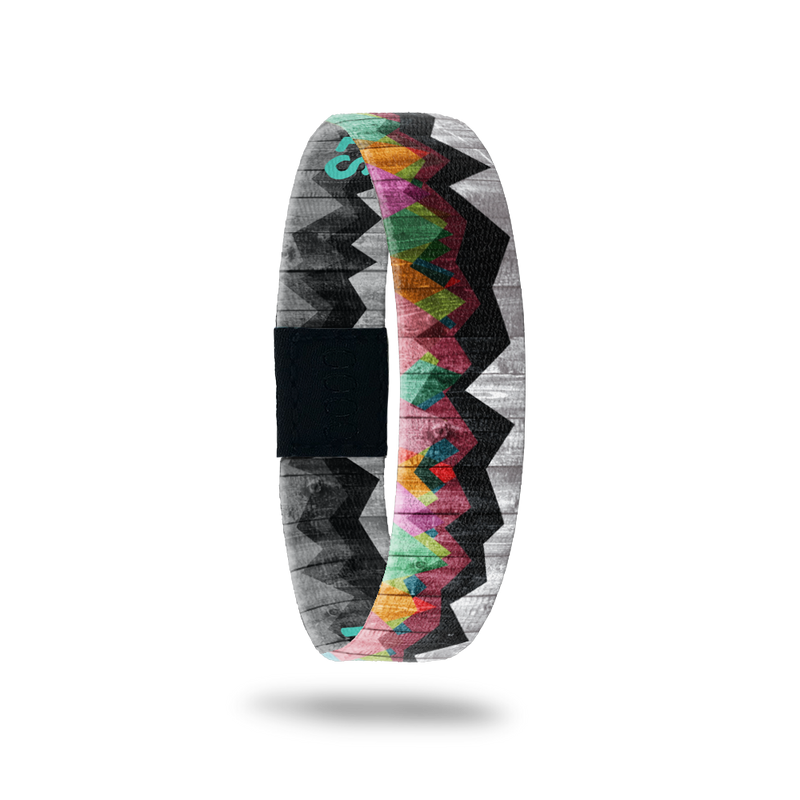 Single wristband with two design in one. The background design is a black and grey weathered picket fence and has a grainy look to it. Over top about 3/4 showing, is abstract mountains of varying colors. The inside is the same design and reads Mountains to Molehills. 