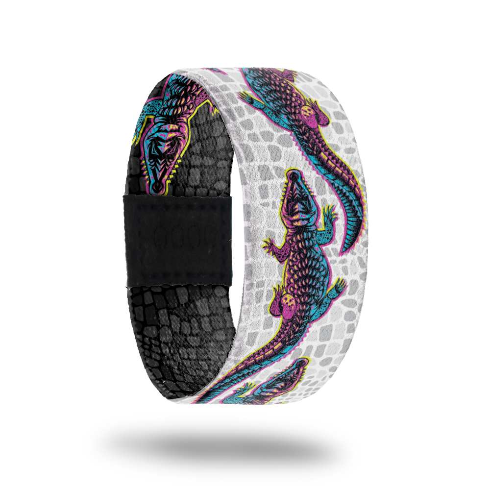 product image of the outside of a wristband called Make your Own Path. The background is a white and grey version of alligator scales. On top are multi-color alligators one after another for the entire design. Each alligator is a gradient that is pink, yellow, and blue
