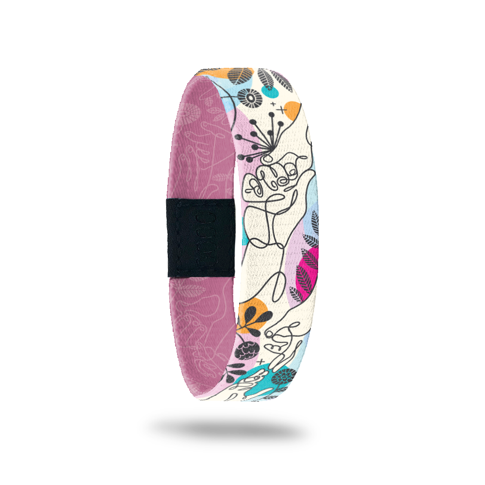 Wristband single with an abstract line drawing of two people holding hands. There are abstract flowers and shapes all over with colors of pink, gold, blue and purple. The inside is the same design in a monochromatic dusty pink and reads My Hand In Yours. 