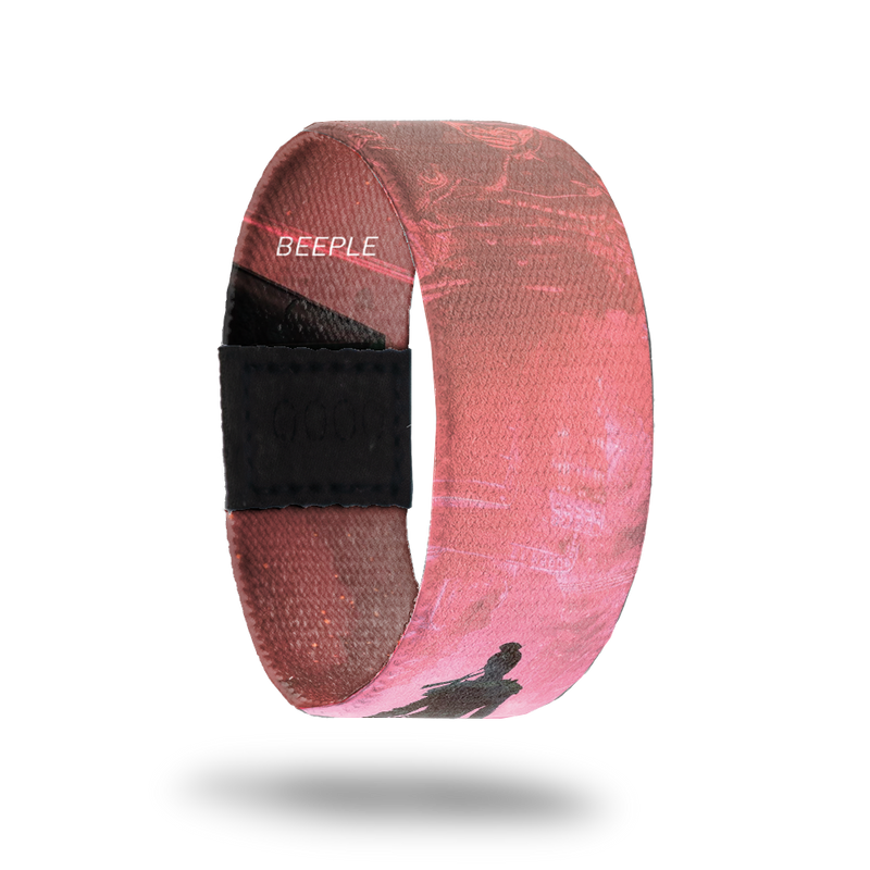 outside product photo of a wristband named Show Up designed by Beeple. It is mainly pink and red and features a darker silhouette of a warrior walking down a road to a larger lighter colored warrior that appears to be in the sky 