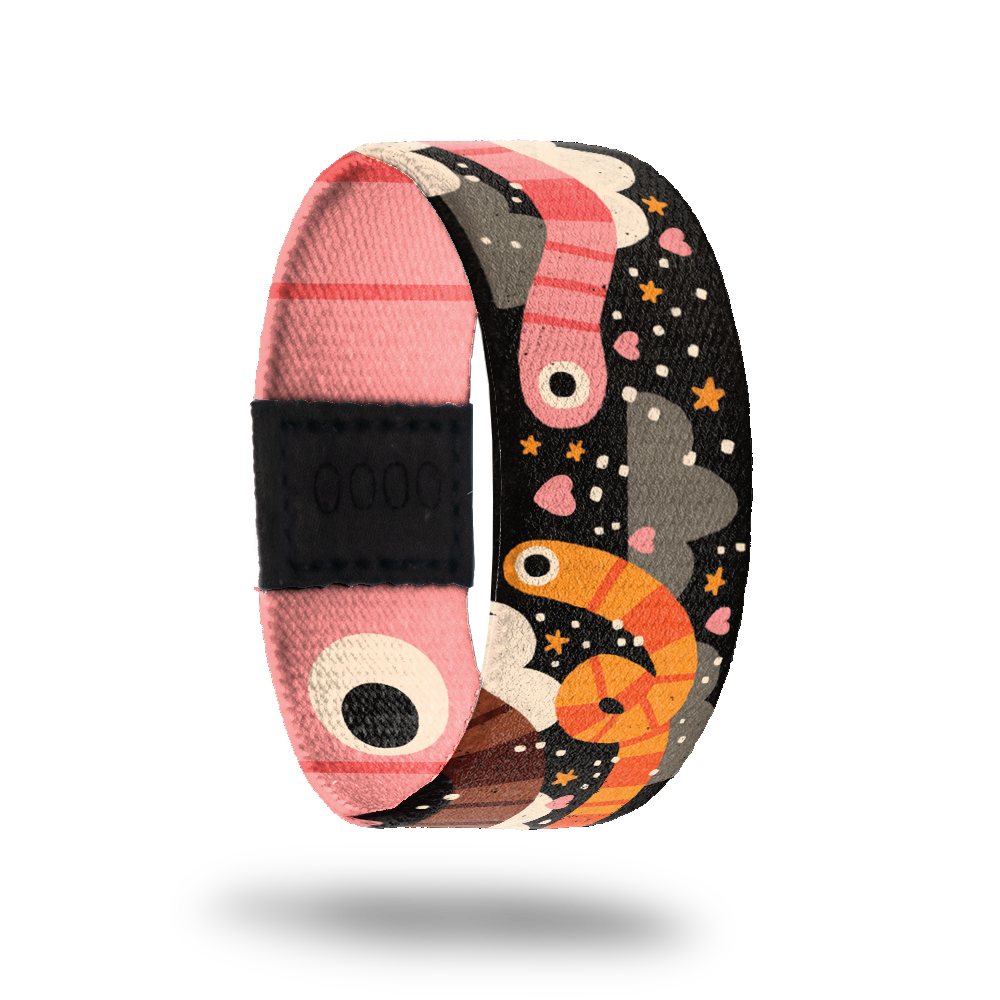 Outside is black with orange and pink striped worms. Hearts, stars and dots with black clouds. Inside is pink striped with big worm eyes and reads "Slide On Over". Comes with an enamel pin of a pink striped worm.