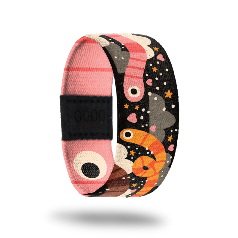 Outside is black with orange and pink striped worms. Hearts, stars and dots with black clouds. Inside is pink striped with big worm eyes and reads "Slide On Over". Comes with an enamel pin of a pink striped worm.