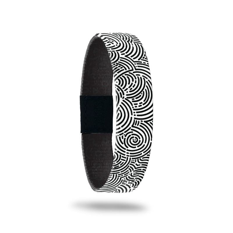 Wristband single with a black and white circular maze design all over. The inside is the same and in teal reads One Day At A Time.