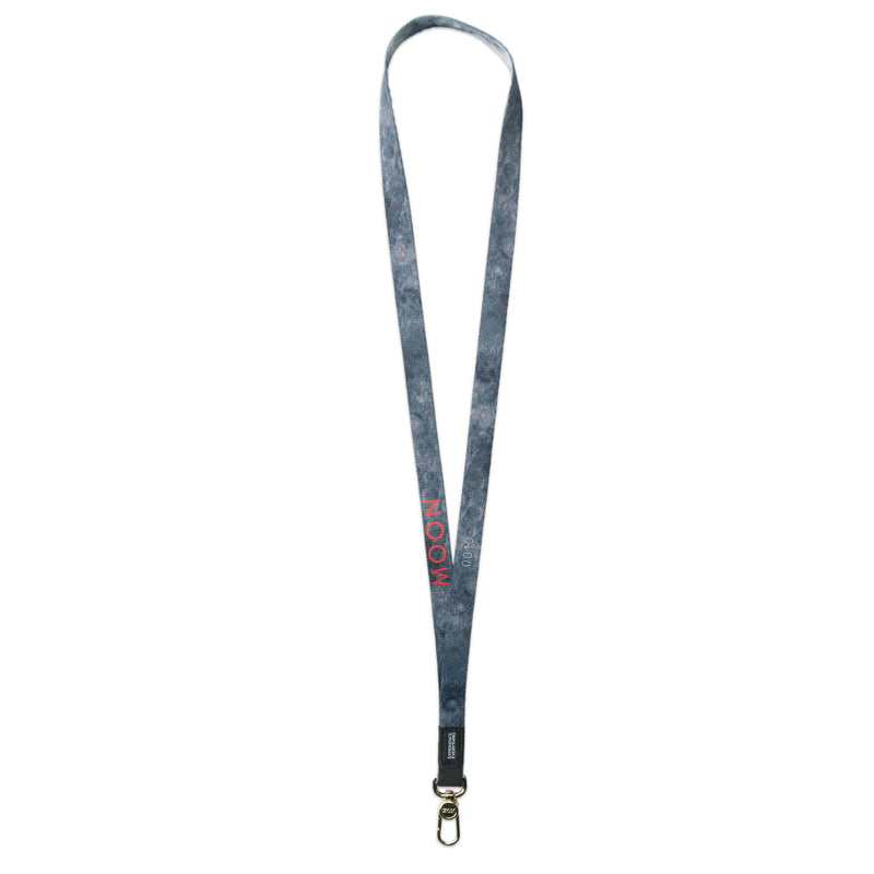 A product image of a ZOX lanyard showing the back of the design with a gold colored metal clip. The lanyard is called and says Moon and the design is a grayscale version of the front design which is an image of the surface of the Moon