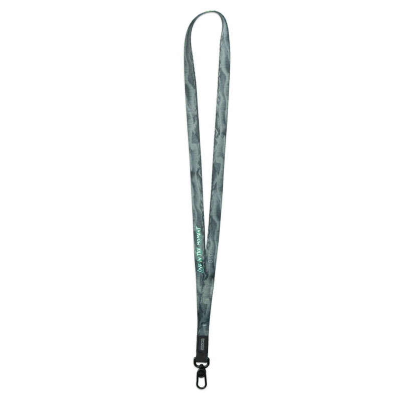 A product image of a ZOX lanyard showing the back of the design with a black colored metal clip. The lanyard is called and says Live In The Moment and the design is a grayscale version of the front design which is the northern lights