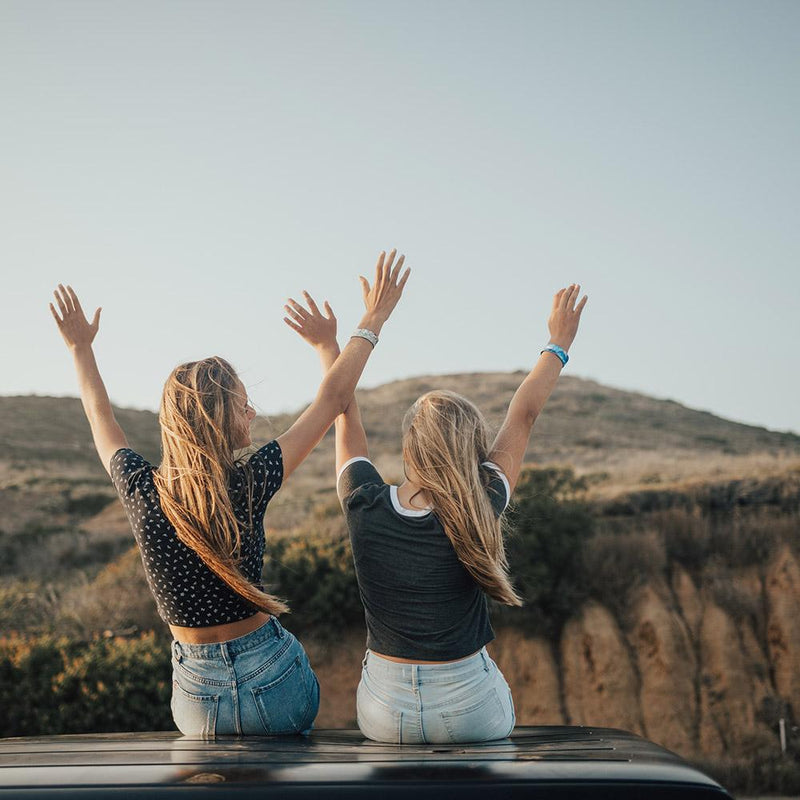 Two Models wearing Be Your Hero on their right hand while raising their arms up in the air.