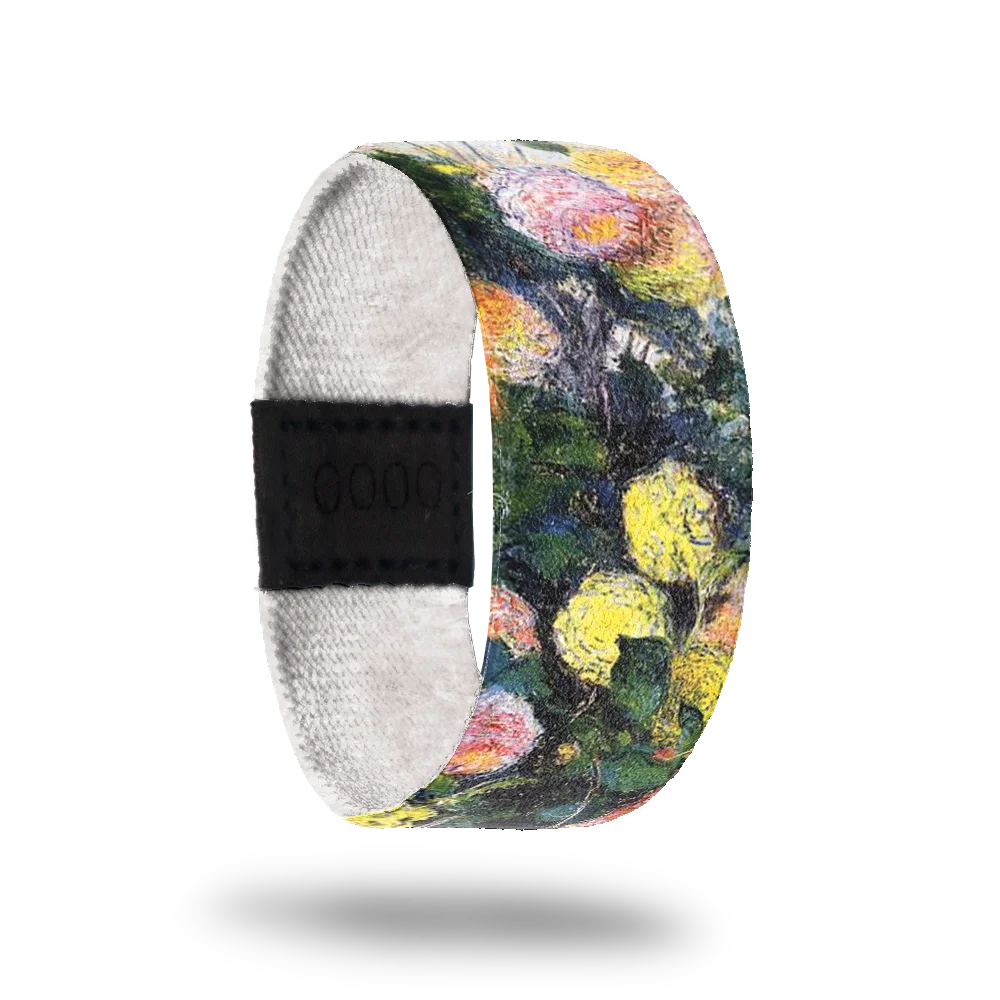 This is a reversible strap. The design is a watercolor painting of flowers in green, red and yellow. The inside of the band is all white and reads Dahlia. 
