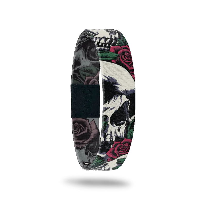 Wristband single with a design of white and grey skulls up close intertwined in roses and leaves; very grunge looking. The inside is the same design except in all black and white and reads Memento Mori. 