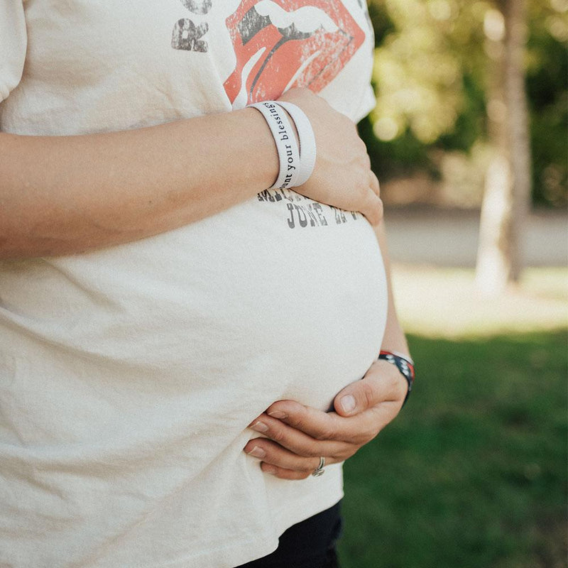 Lifestyle image of pregnant women holding her belly with Count Your Blessings on one wrist