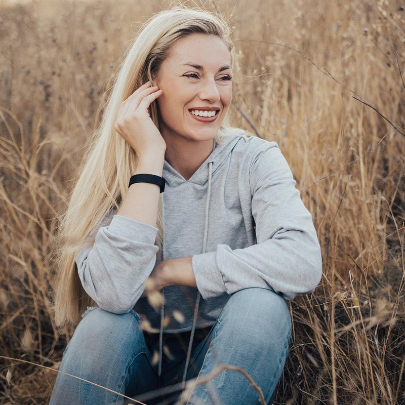 Lifestyle image close up of someone sitting and smiling in a field with Experience Everything on their wrist 