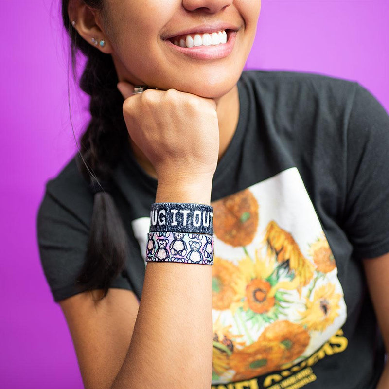 Studio close up image of smiling model and Hug It Out on their wrist