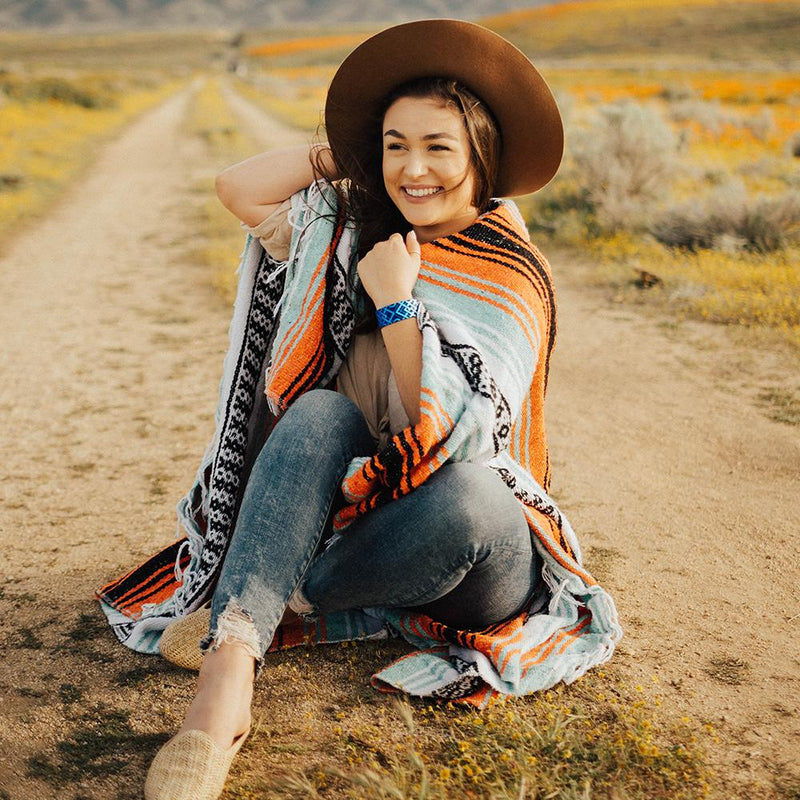 Lifestyle Image of someone sitting and holding onto their hat while wearing I Am Enough