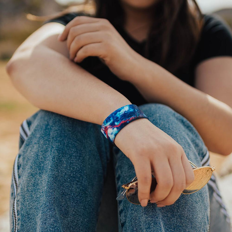 Lifestyle image of someone sitting with arms resting on their knees and I Am ___ on their wrist