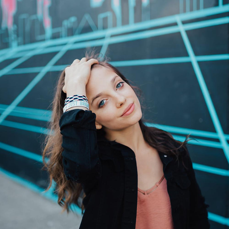 Lifestyle photo of girl wearing a just breathe strap showing inside and outside design, pushing her hair out of her face.