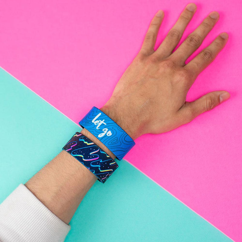 Studio Image of 2 Let Go on a wrist in front of a pink and teal background