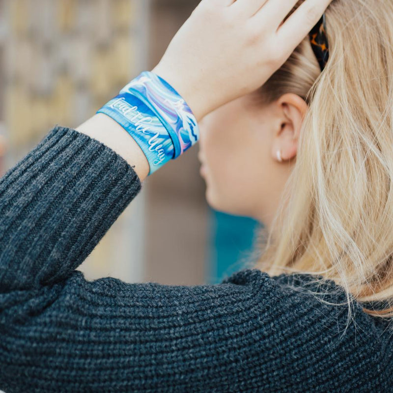 Lifestyle close up image go model fixing their hair and wearing two Lead The Way straps