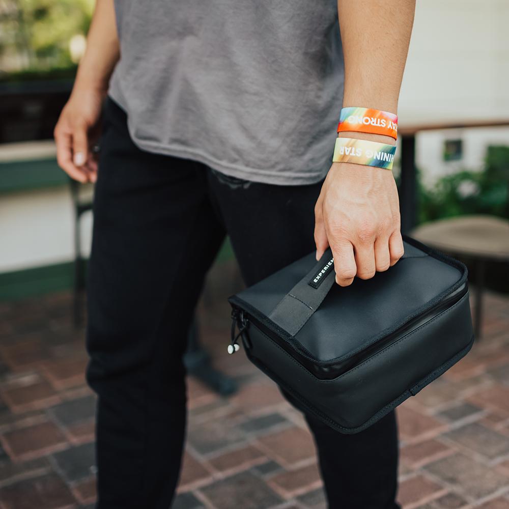 a man holding the lunchbox by the handle that is on the front of it