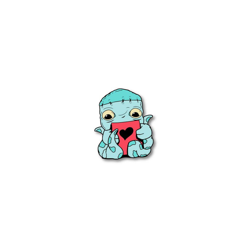 Enamel pin photo for 2020 - Day 21 - Frankie 8-Arms: turquoise and light blue monster with 8 arms holding a red piece of paper with a black heart on it