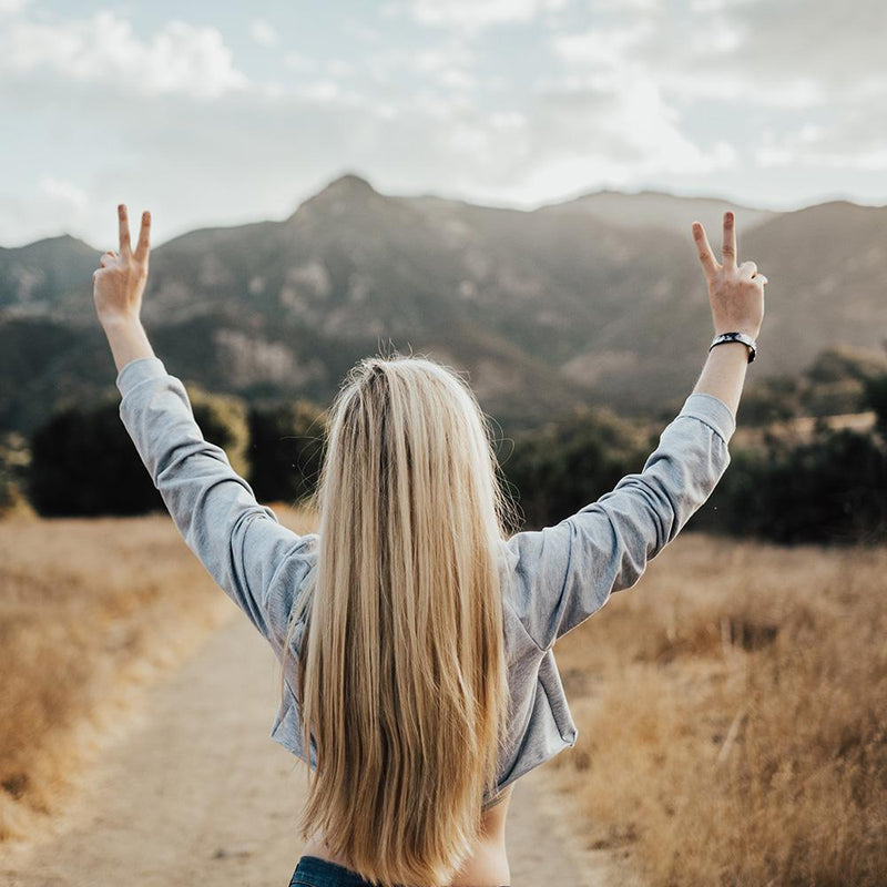 Lifestyle image of someone raising both their hands making the peace sign and wearing Moon