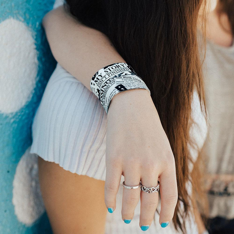 Lifestyle close up of arm resting on someone's shoulder and wearing 2 My Story Isn't Finished wristbands