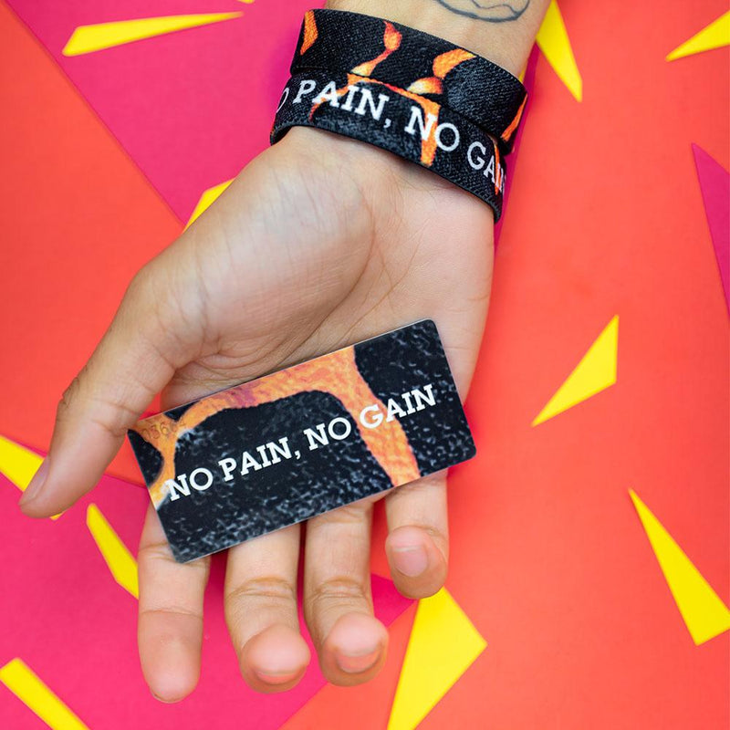 Studio photo of hand holding the number-matching collector's card while wearing two no pain, no gain singles showing the inside and outside design