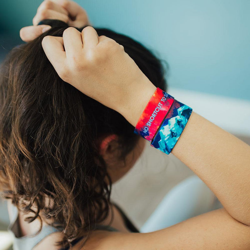 Lifestyle image of someone putting hair in a ponytail and wearing 2 No Shortcut To Success on wrist.