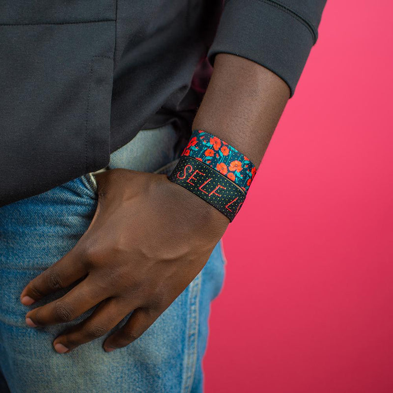 Studio image close up of model's hand in pocket with Self Love on wrist