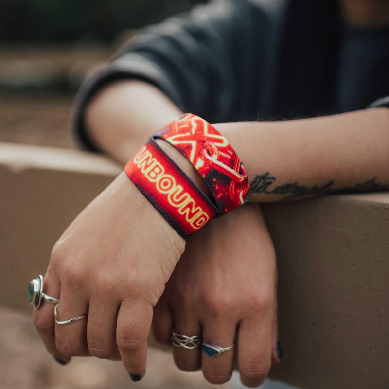 Lifestyle close up image of arms resting on a fence and wearing two Unbound straps