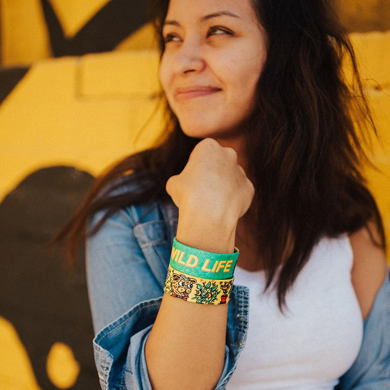 Lifestyle image close up of someone smiling with 2 Wild Life on their wrist 