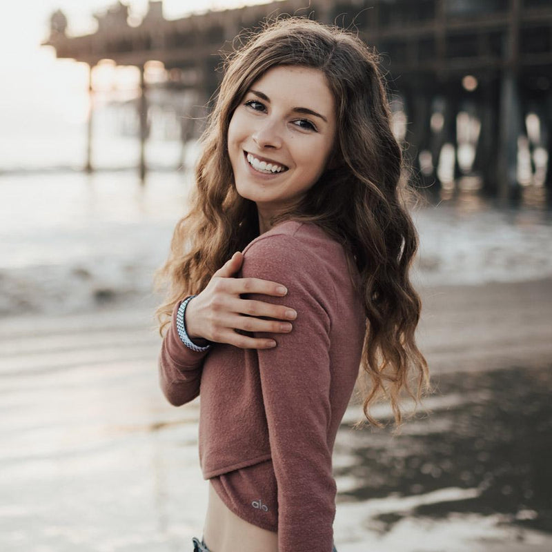 Lifestyle image of someone smiling on the beach wearing You're Not Alone