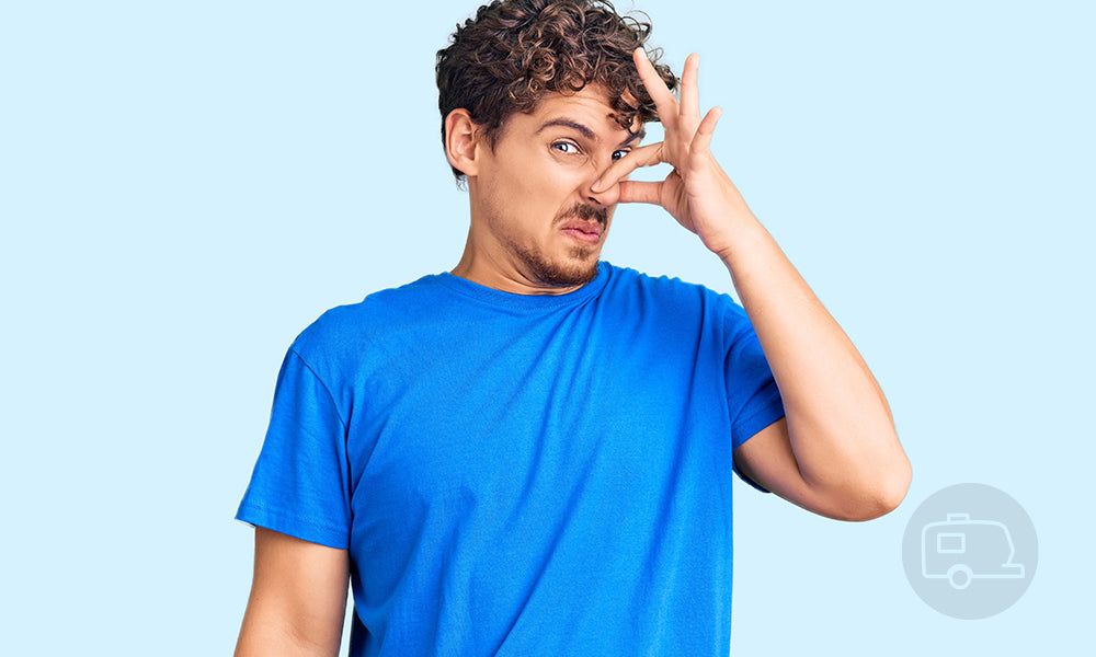 Man in a blue t-shirt covers his nose because of pungent smell. Unique Camping + Marine